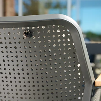 Detailaufnahme einer perforierten Rückenlehne eines Outdoor Stuhls aus grauem Metall.