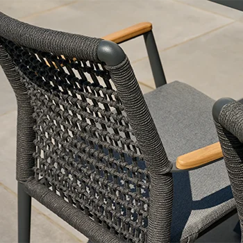 Detailaufnahme eines modernen Gartenstuhls mit geflochtener Rückenlehne aus dunkelgrauem Rope, Holzarmlehnen und gepolsterter Sitzfläche.
