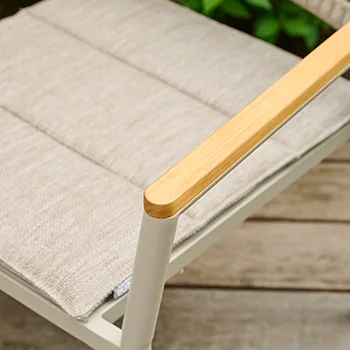 Detailaufnahme einer hellen Outdoor Stuhlarmlehne aus Holz mit beigefarbenem Sitzpolster.