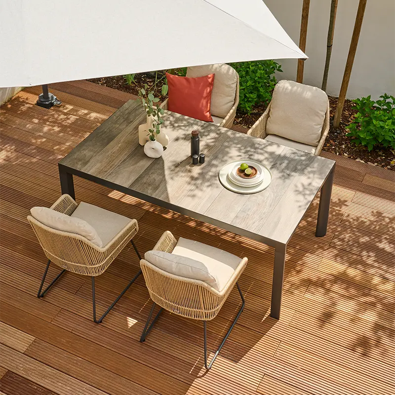 Moderne Outdoor Essgruppe mit Tisch, vier gepolsterten Lounge Stühlen unter einem Sonnenschirm auf einer Holzterrasse.