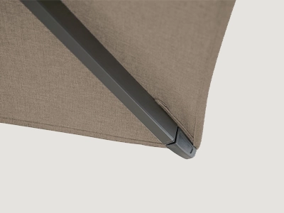 Detail einer dunklen Schirmstrebe mit Endkappe an einer beigefarbenen Schirm-Bespannung.