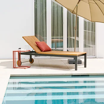 Moderne Gartenliege aus Holz und Metall mit rotem Kissen neben einem Beistelltisch auf einer Terrasse am Pool.