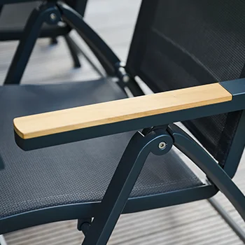 Detailaufnahme einer schwarzen Outdoor‑Stuhlarmlehne aus hellem Holz auf Metallgestell.