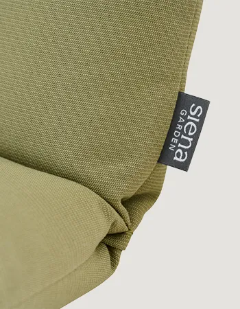 Detailaufnahme einer grünen Sitzauflage mit seitlichem Logo-Etikett und leicht gefalteter Kante vor hellem Hintergrund.