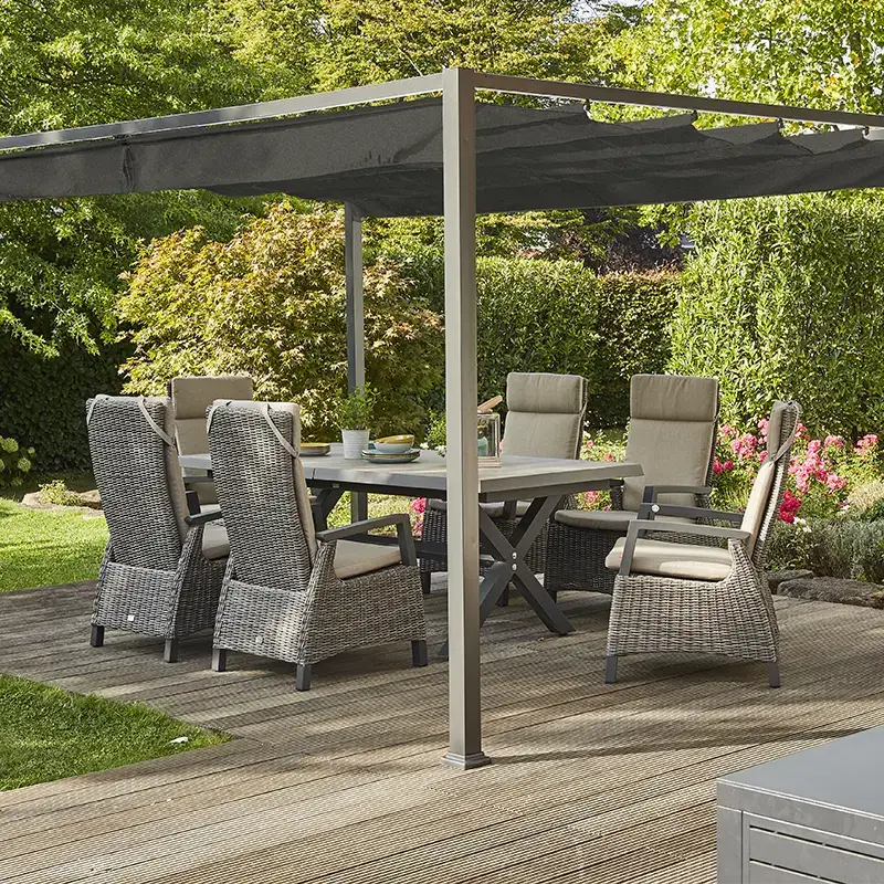 Moderne Outdoor Essgruppe aus grauem Geflecht und Polsterstühlen unter einer Pergola auf einer Holzterrasse im grünen Garten.