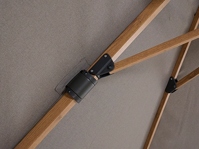 Blick unter das beigefarbene Schirmdach auf das Streben Gelenk in Holzoptik.