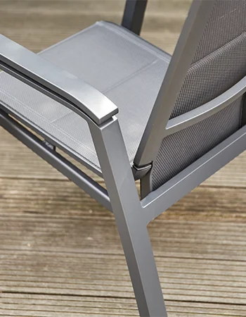 Nahaufnahme eines Gartenstuhls mit grauem Metallrahmen und feinmaschiger Textilbespannung auf einem Holzdeck.