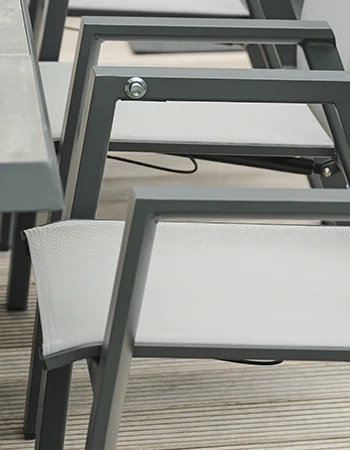 Detailaufnahme eines grauen Outdoor Stuhls mit Textilgewebe Sitzfläche und eckigem Metallrahmen.